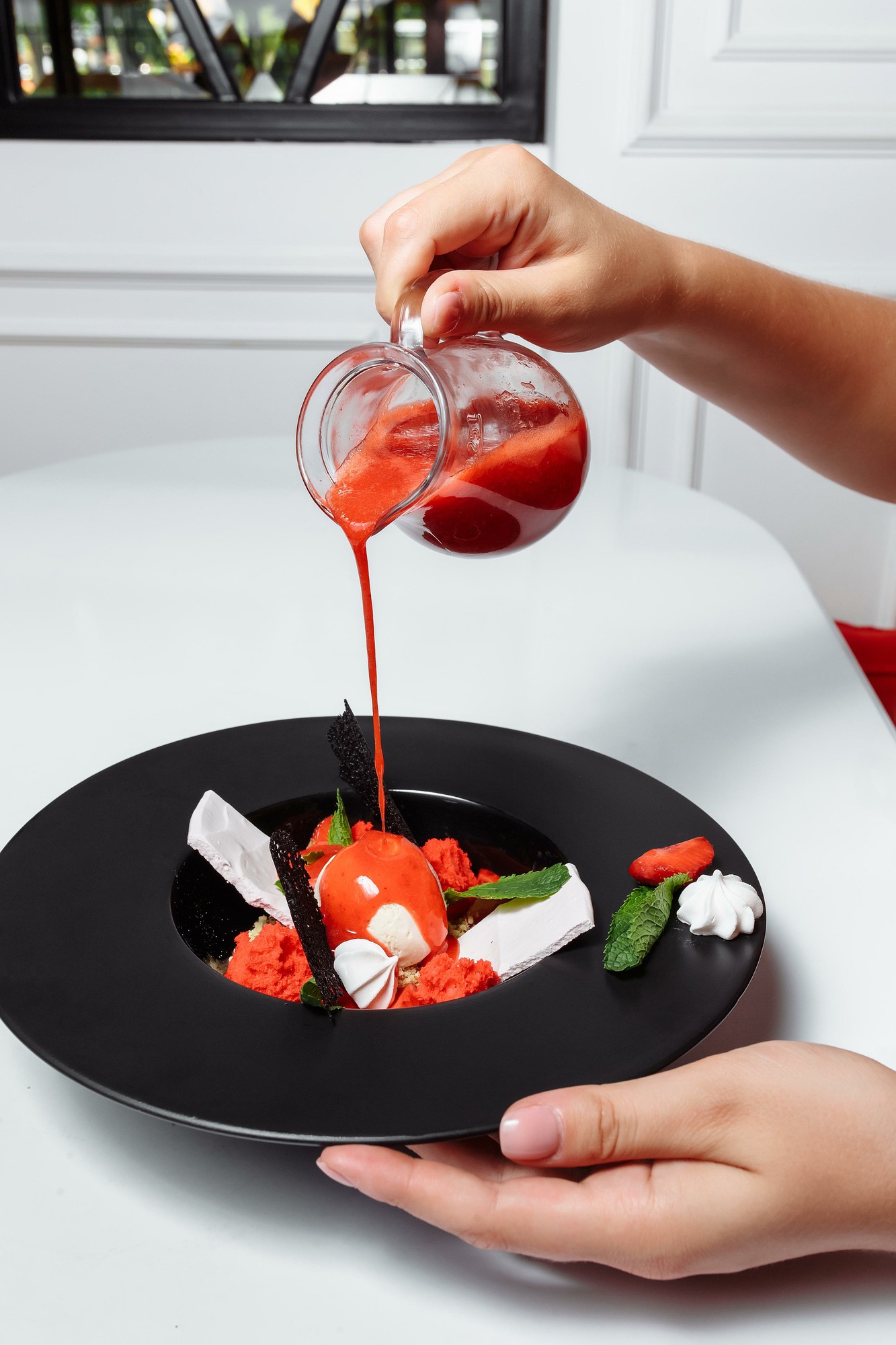 Hands plating a composed dish